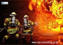 training fireman sedang mempraktikkan pemadaman api dengan alat pemadam kebakaran dalam simulasi lapangan.